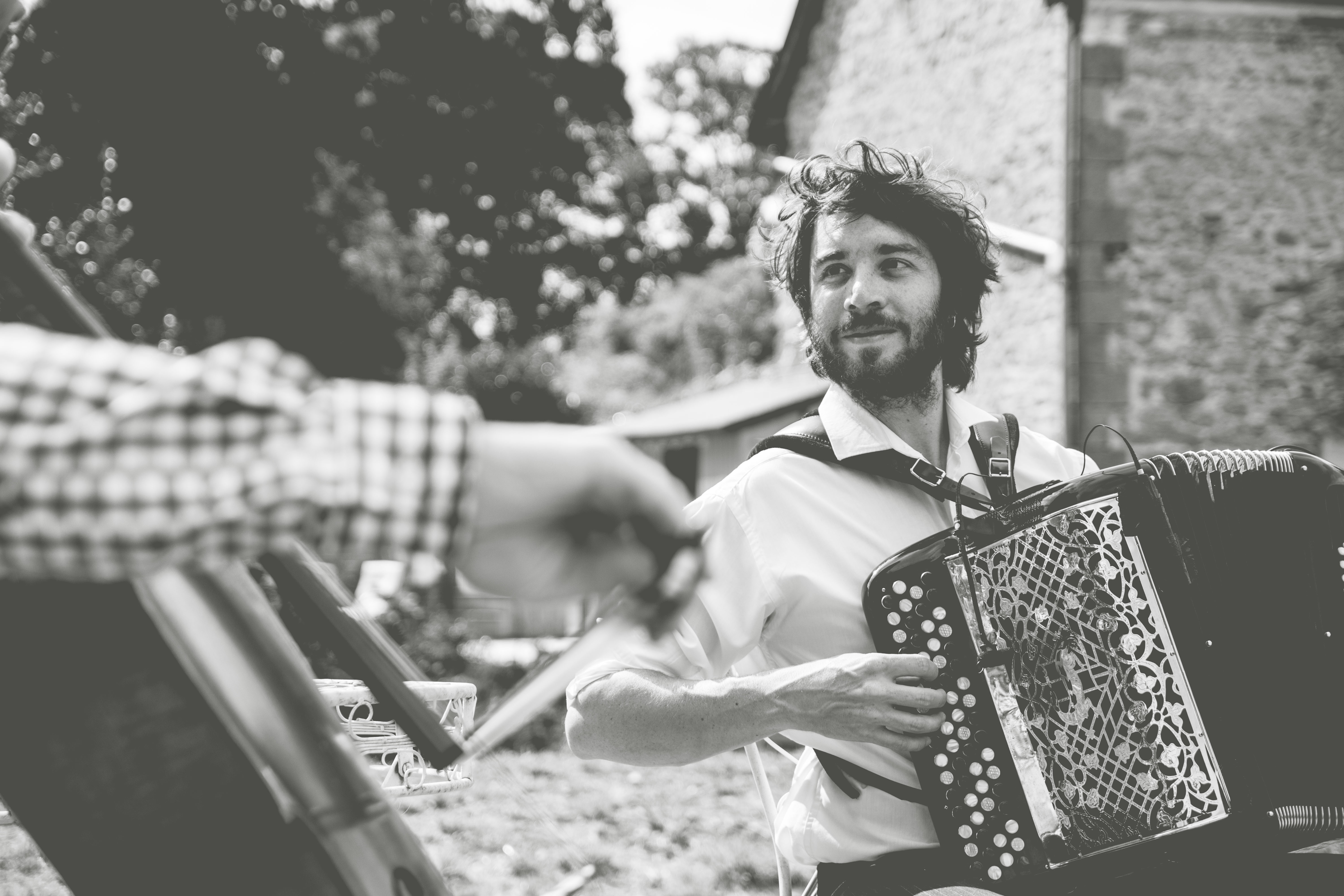 Black and white image of a French man playing accordion at a wedding