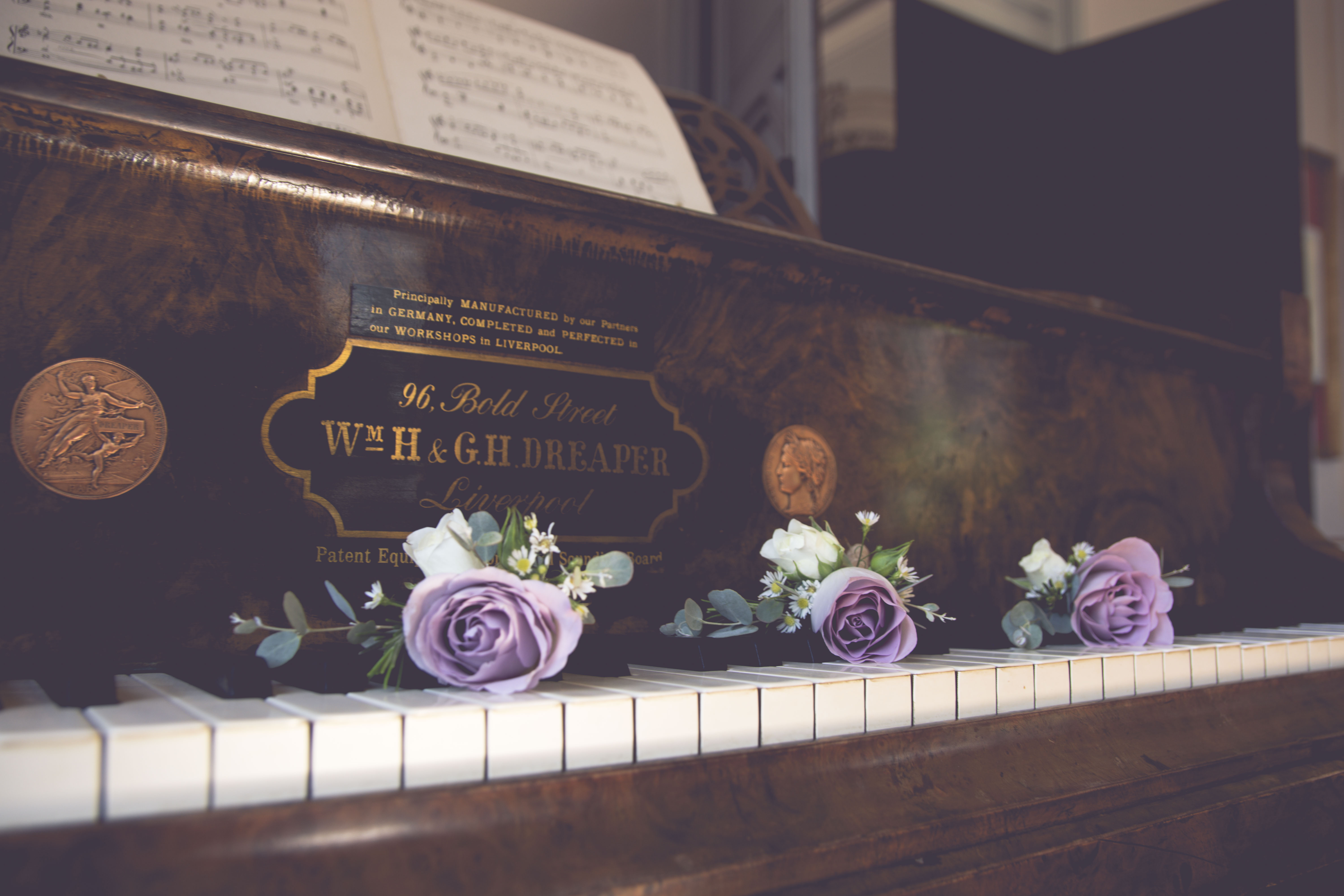 An image of purple rose boutonnières sitting on a vintage piano