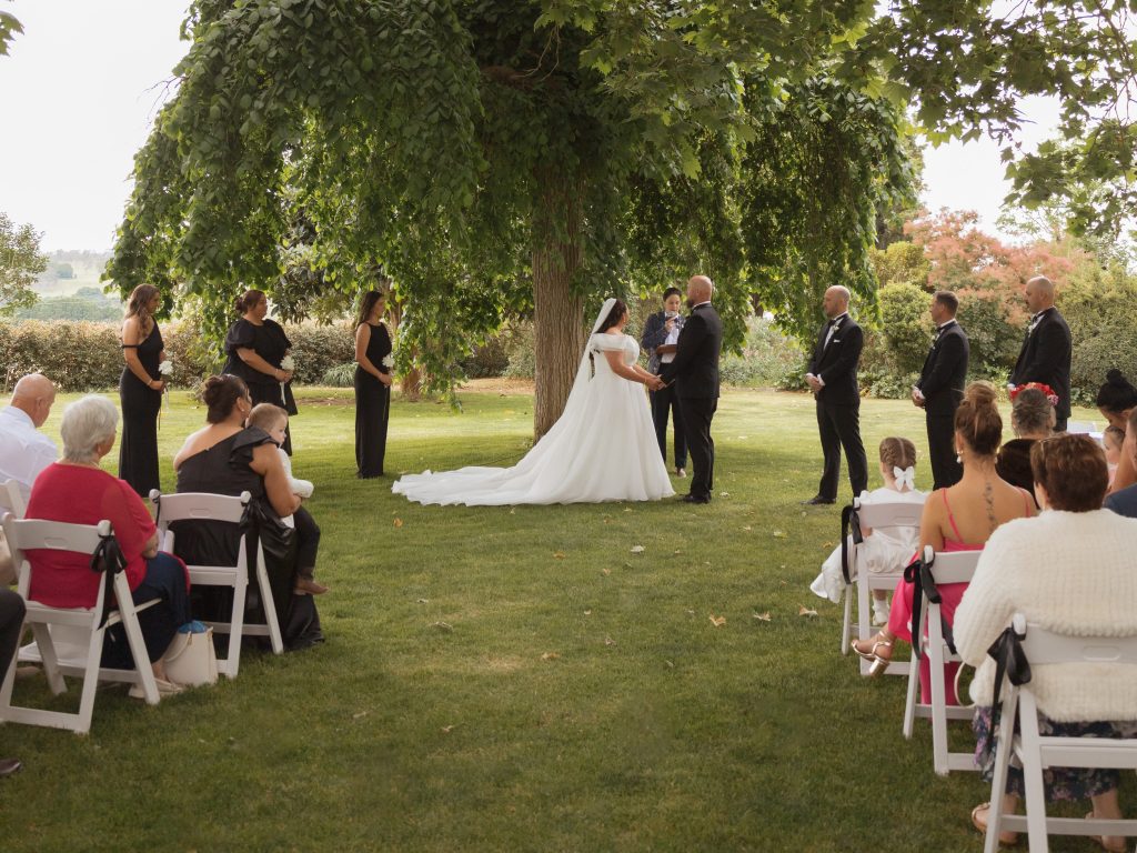 A colour wedding photo by Studio LJ with SJF officiating a ceremony underneath a big tree